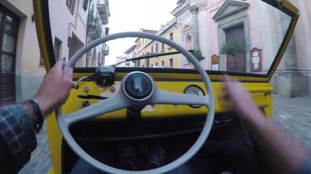 Man driving his yellow car in a desolated city. On side characteristic houses and cobbled street
