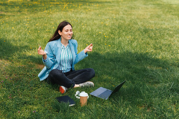 Photo of happy woman in casual sitting on grass in park and taking a rest and meditating