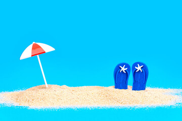 Blue flip flops in sand. Miniature toy composition.
