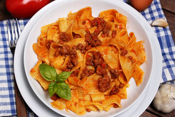 Gustoso piatto di pappardelle all'uovo condite con sugo di cinghiale e foglie di basilico.