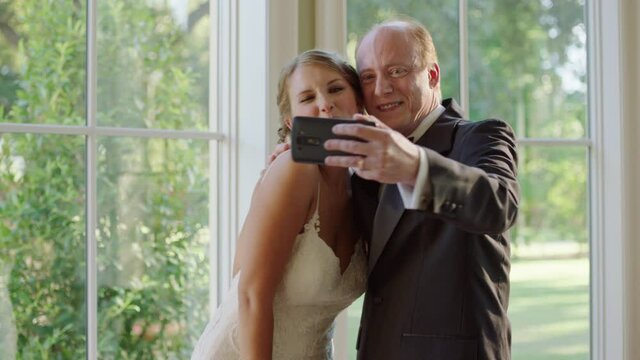 A proud father taking a picture with his daughter before her wedding ceremony.