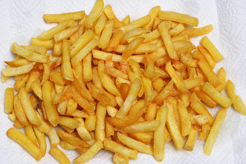 Primo piano fotografico di patate fritte disposte su un foglio di carta assorbente.