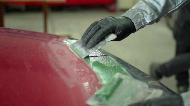 A Man Applies Base To A Damaged Car. Preparation For Painting The Defective Part Of The Car