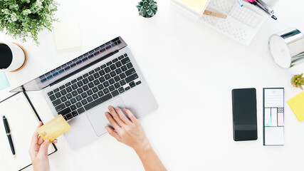 Top view of freelance Asia lady casual using laptop online shopping with credit card on table in living room at house. Working from home, remotely work, social distancing, quarantine for coronavirus.