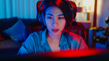 Close-up face happy asia professional girl gamer wear headphone competition play video game neon...