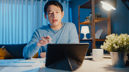 Asia businessman focus online video call meeting assignment on paperwork with colleague in tablet...