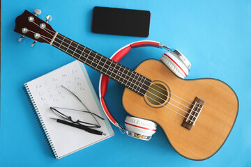 Fototapeta premium Guitar with headphones smartphones and notebook on blue background
