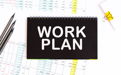 WORK PLAN. informationon on a sticker, on a blue background desktop .. informationon on a black notebook, on a background office table.