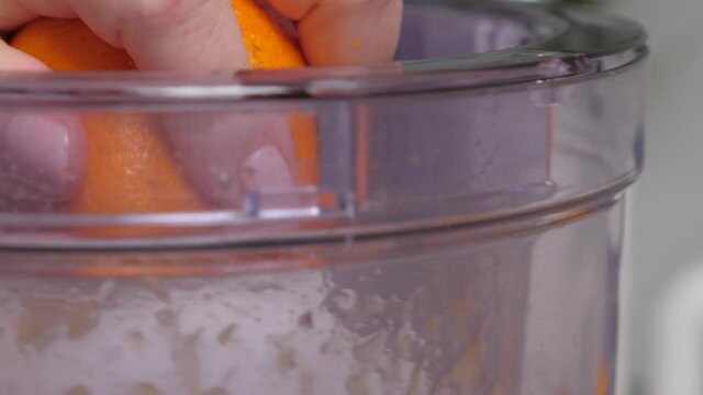 Woman preparing orange juice in juicer. Squeezing procces