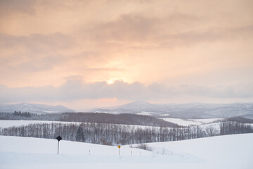 Fototapeta na wymiar Tokachidake, Biei, Hokkaido, Japan, the warm yellow sunset and snow-white hills are amazing