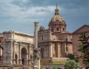 Obraz premium Rome Italy, trionfal arch of Septimus Severus Caesar and Santa Martina church under an impressive sky with sun rays