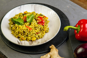 Food for suhoor in Ramadan bulgur post with vegetables in a plate on a gray background near vegetables on a board.