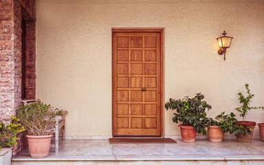 Fototapeta na wymiar elegant house front external natural wood door and flowerpots, Athens Greece