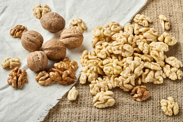 peeled and whole walnuts on a background of white and brown textured fabric