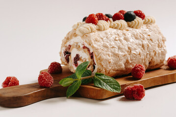Meringue roll with a gentle airy cream, mint and fruit filling from raspberries, black currants, blueberries. Pavlova summer sweet dessert