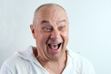 close-up face of a middle-aged man, a senior in white looks, laughs cheerfully, the concept of...