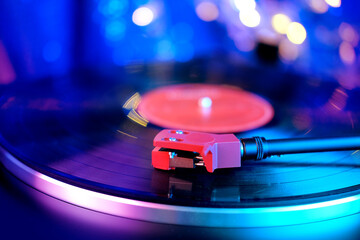 close-up of a pickup head on a vinyl record, color illumination, analogue retro music concept, audio experience, relaxation, musical enjoyment, vintage technology © kittyfly