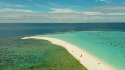 Obraz premium Tropical white island and sandy beach with tourists surrounded by coral reef and blue sea, aerial view. Sandbar Atoll. Island with sand bar and coral reef. Summer and travel vacation concept, Camiguin
