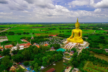 Aerial view of big golden buddha statue with green rice field background at Wat Muang, Ang Thong...