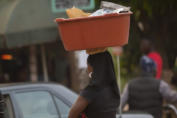 African woman carrying a plastic basket on her head
