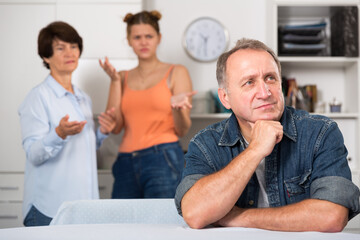 Adult man is upseting and his wife with daughter are sympathying with her at home.