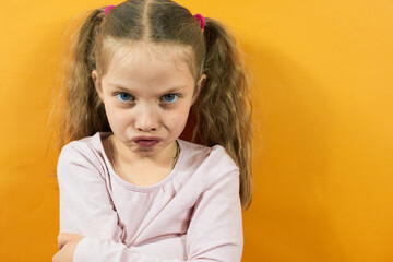 portrait of an angry little girl on a yellow background, emotions in children