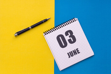 June 3rd. Day 3 of month, calendar date. Notebook with a spiral and pen lies on a yellow-blue background