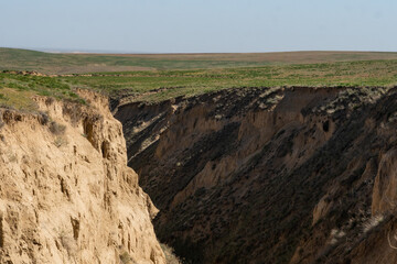 Endless steppe in the valley at the foot of the mountains, bathed in bright sunlight. Amazing view on  green mountains. mountain, covered with green trees, under a blue sky with clouds.
