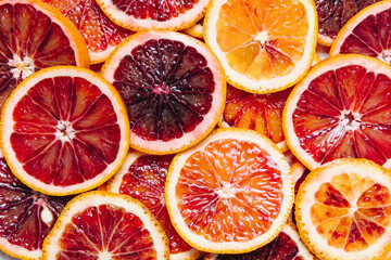 Bright colorful background of fresh ripe sliced blood oranges. Close up, flat lay, top view. Orange...