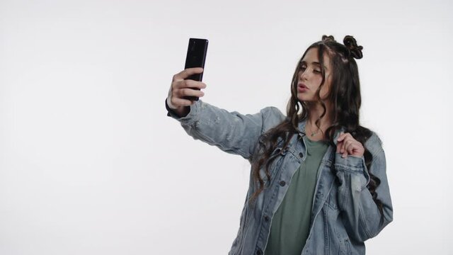 Playful young hipster girl poses for selfies on white space