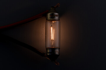 Car classic halogen bulb. Filament, glass and metal, high energy consumption. Black background. interior lighting. energized, working condition. Lights up