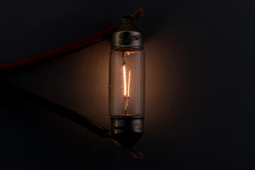 Car classic halogen bulb. Filament, glass and metal, high energy consumption. Black background....