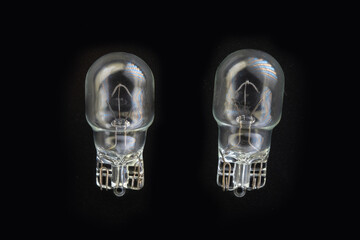Automotive classic halogen bulb. Filament, glass and metal, high energy consumption. Black background. Close-up view. copy space. w10w