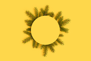 Round paper card mockup with frame made of spruce branches. Festive layout on a yellow background.