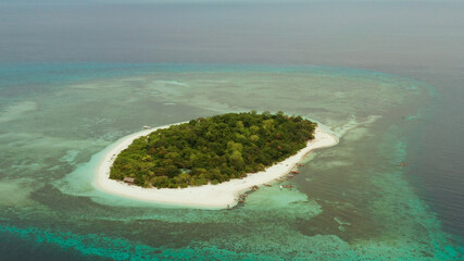 Tropical island Mantigue and sandy beach surrounded by atoll coral reef and blue sea, aerial view....