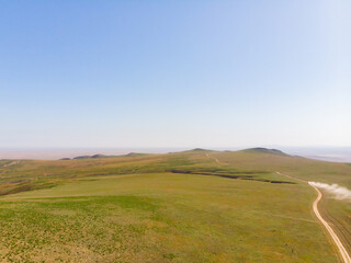 Obraz premium Endless steppe in the valley at the foot of the mountains, bathed in bright sunlight. Amazing view on green mountains. mountain, covered with green trees, under a blue sky with clouds.