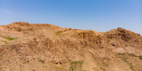 Endless steppe in the valley at the foot of the mountains, bathed in bright sunlight. Amazing view on  green mountains. mountain, covered with green trees, under a blue sky with clouds.