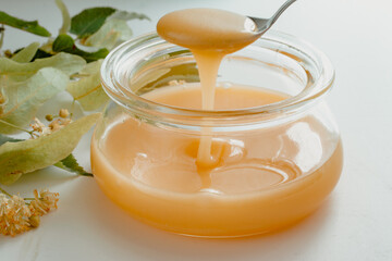 a glass jar of honey with linden flowers on a white background.The concept of healthy eating. Treatment of colds with honey. horizontal image