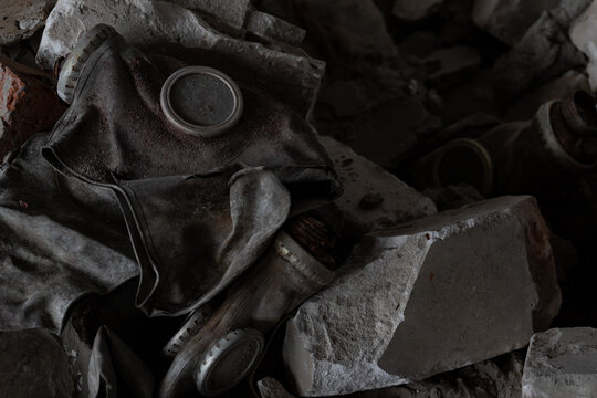 Torn and dirty old Soviet Gas masks of the Soviet era lie in the rubble of the walls of an abandoned destroyed building made of bricks and concrete left over from liquidators and the Russian army.
