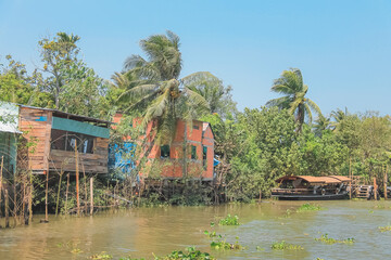 Traditional Vietnamese riverside stilt houses along the Hau (Bassac) River at the Mekong Delta near...