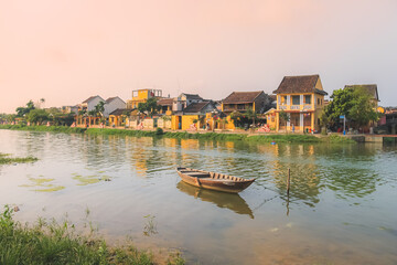 Obraz premium A lone traditional Vietnamese boat on Thu Bon River during a golden sunset in the quaint old town village Hoi An, Vietnam.