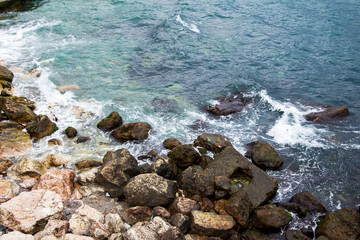 The sea splashes against the stones. The concept of sea rest, relaxation. Waves run onto the shore and crash against rocks, creating splashes.