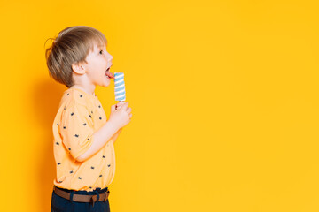 Little boy holding striped ice cream on a stick in his hands. Summertime
