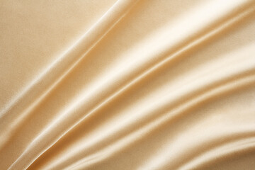 shiny light golden fabric draped with large folds, textile background