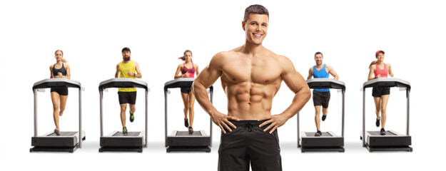 Topless muscular man posing in front of young people running on treadmills