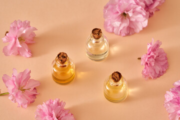 Obraz na płótnie Canvas Essential oil bottles with kwanzan cherry blossoms in spring on orange background