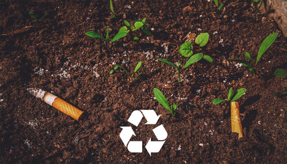 Recycling logo. Closeup top view of cigarettes on the grown grass. Concept of earth pollution and...