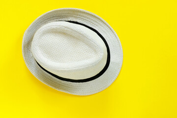 Fashionable straw hat on yellow paper background.