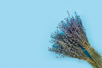 Fototapeta premium Bouquet of dry purple fragrant lavender on blue paper background. Great for greeting-card.