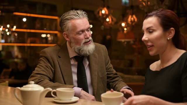 Male interlocutor listens attentively to his girlfriend during a conversation over a cup of tea in a bar
